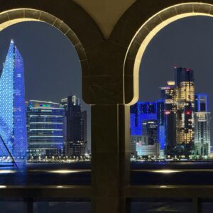 Stunning night view of Doha skyline seen through decorative archways, reflecting vibrant city lights. kwesttzadventures Doha