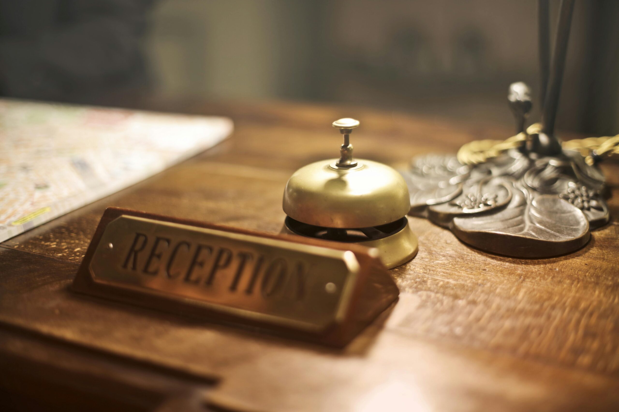 Old fashioned golden service bell and reception sign placed on wooden counter of hotel with retro interior, kali travels