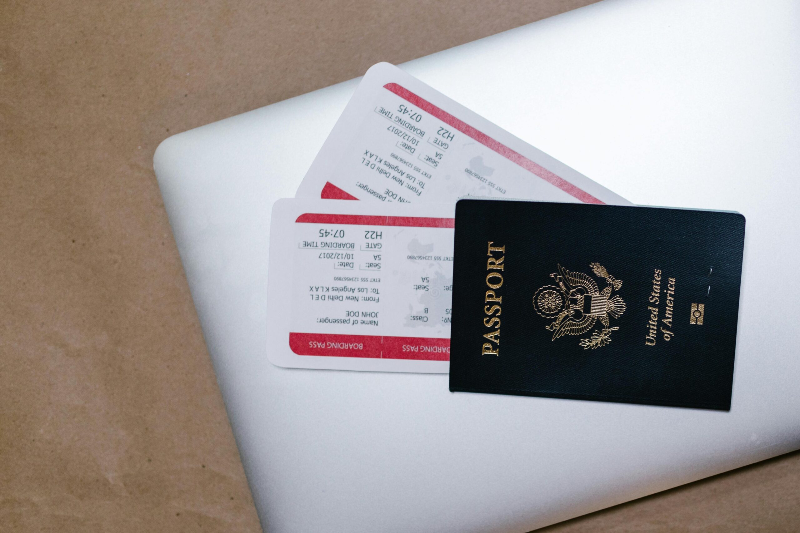 Close-up of a passport and boarding passes on a laptop, symbolizing travel preparation. kali travels